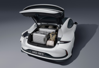 Open boot of white MG IM5 car with luggage and a handbag inside.