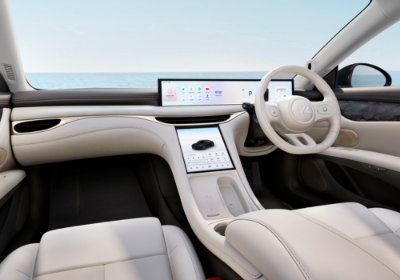 Luxury car interior with beige leather seats and a large touchscreen dashboard display.